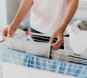 Someone's hands hanging laundry on a drying rack