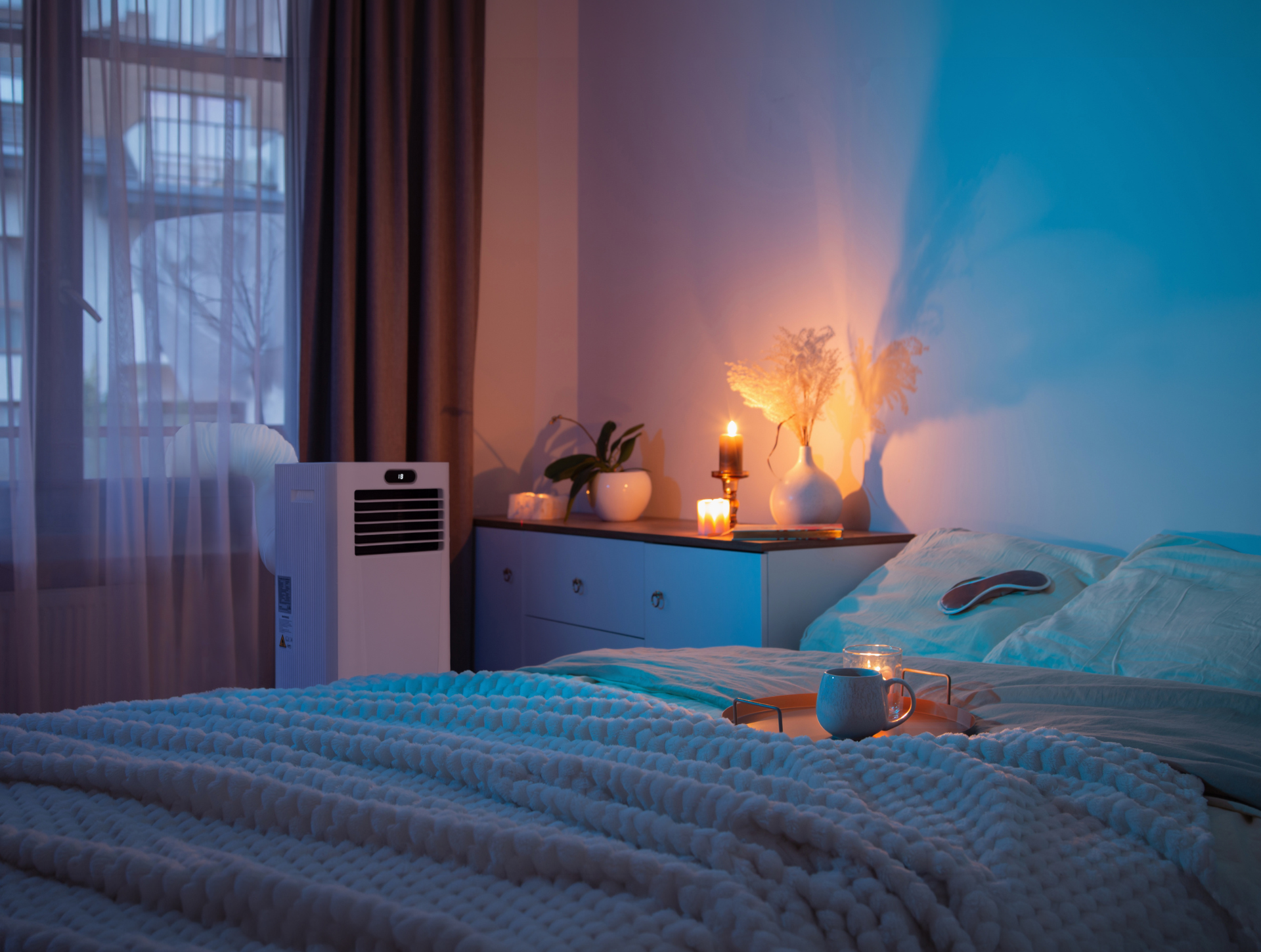 Die MeacoCool Klimaanlage steht neben einem Bett.